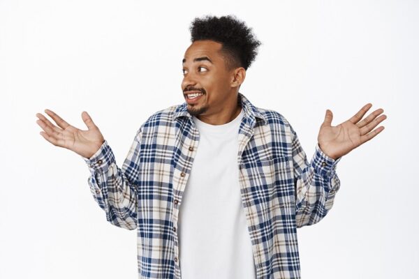 Oops awkward. Confused african american man shrugging shoulders, looking worried, raising empty hands up, dont know how accident happened, made small silly mistake, white background.